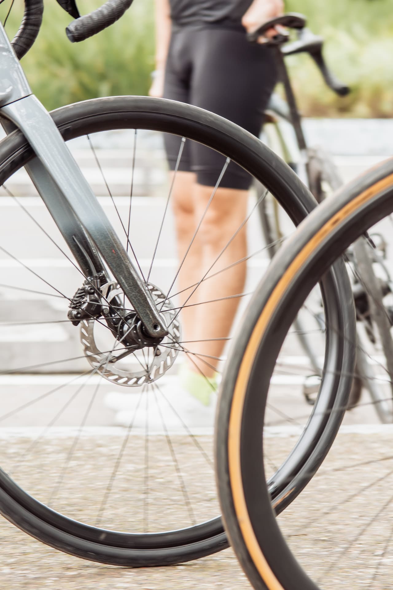 Ruedas de bicicletas de ruta y una ciclista con bib negro al amanecer en La Marquesa